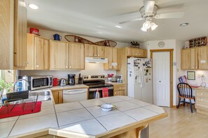 A kitchen with wooden cabinets, a microwave, a stove, and a refrigerator. - Yellowstone Basecamp! Emigrant Home w/ Mtn Views (Emigrant)