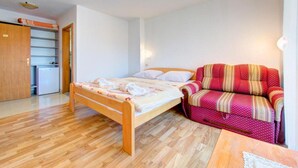Et soveværelse med en træseng, en rød sofa med mønster og en træskab.