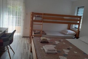 A bunk bed room with a desk and chair, a window with curtains, and a patterned rug. - Glory Sanctuary Retreat - Family room (Medugorje)