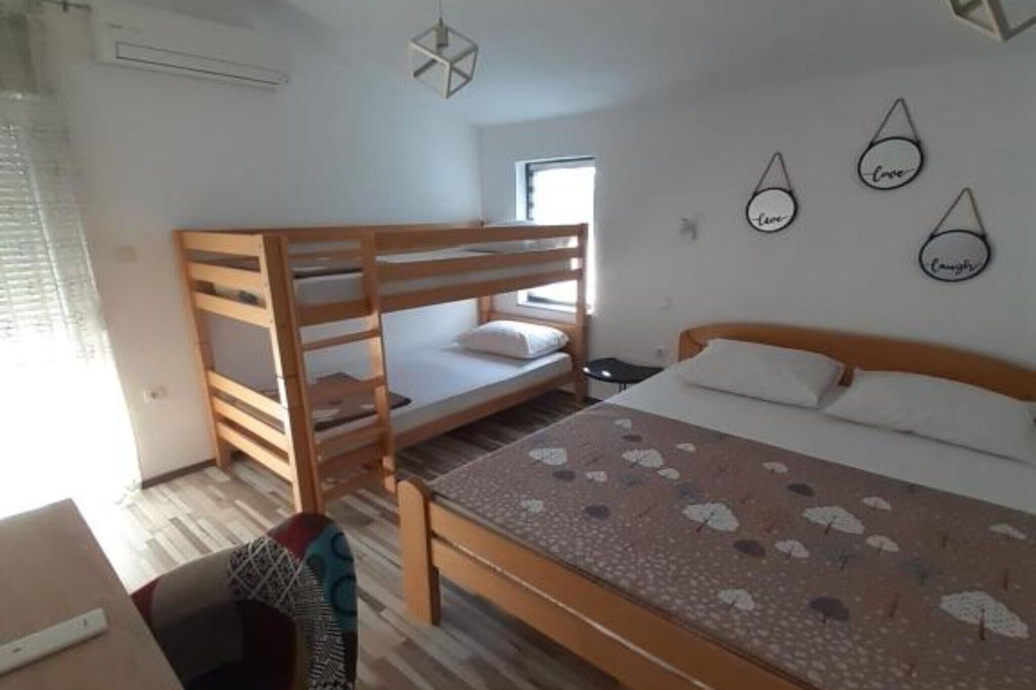 A room with bunk beds, a bed with a patterned bedspread, a small table, and wall decorations.
