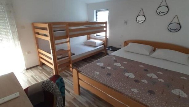 A room with bunk beds, a bed with a patterned bedspread, a small table, and wall decorations. - Glory Sanctuary Retreat - Family room (Medugorje)