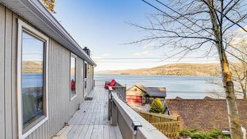Une terrasse en bois offrant une vue sur un lac et des collines.