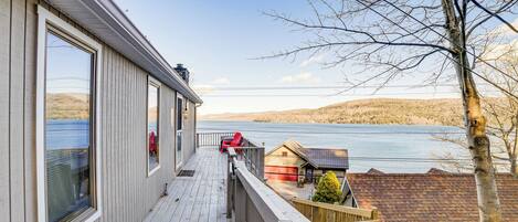 Une terrasse en bois offrant une vue sur un lac et des collines.