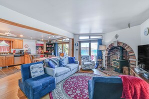 A spacious living room with a fireplace, a kitchen area, and a dining space. - Lakeside Retreat Near Nat’l Baseball Hall of Fame! (Cooperstown)