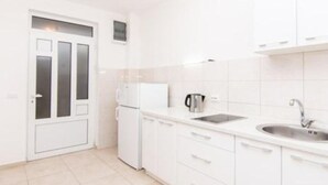 Una cocina moderna con armarios blancos, horno empotrado, fregadero y cafetera.