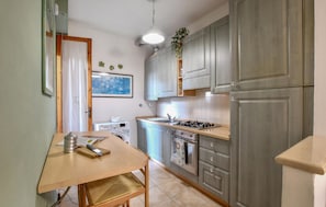 Una cucina compatta con un tavolo in legno, forno integrato e mobili grigi.