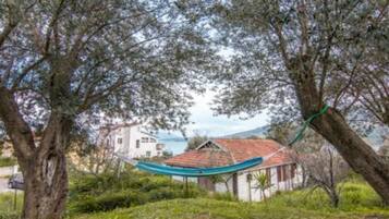 Une maison avec un toit recouvert de tuiles rouges, entourée d’arbres et offrant une vue sur la mer.
