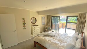 Ein Schlafzimmer mit einem Bett, einem Schminktisch, einem Stuhl und einer Schiebetür, die auf einen Balkon führt.