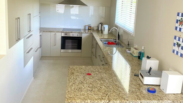 Eine moderne Küche mit Backofen, Edelstahlgeräten, einer Arbeitsplatte aus Granit und zwei Barhocker.