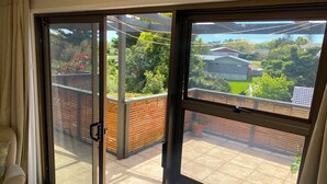 Ein Zimmer mit einer Schiebetür zu einem Balkon mit Blick auf ein Wohngebiet.