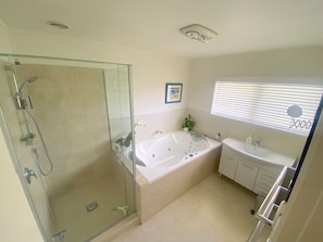 A bathroom with a glass-enclosed shower, a freestanding bathtub, and a vanity with a sink. - Bright 2-Bedroom in East Auckland! (Auckland)