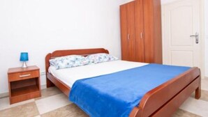A bedroom with a bed, a nightstand, a wardrobe, and a door. - Apartments Savić near the Sea 7 (Herceg Novi)