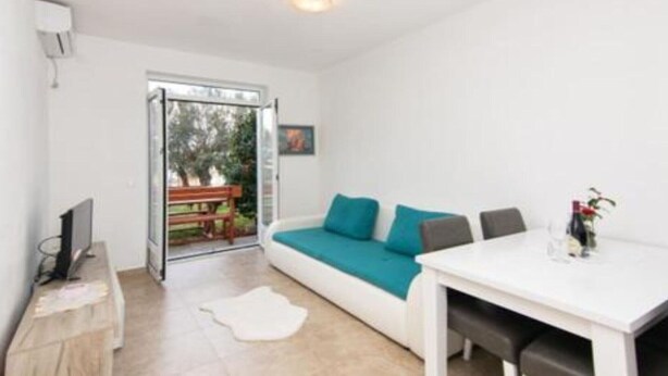 A modern living room with a sofa, a dining table, and a TV. - Apartments Savić near the Sea 7 (Herceg Novi)