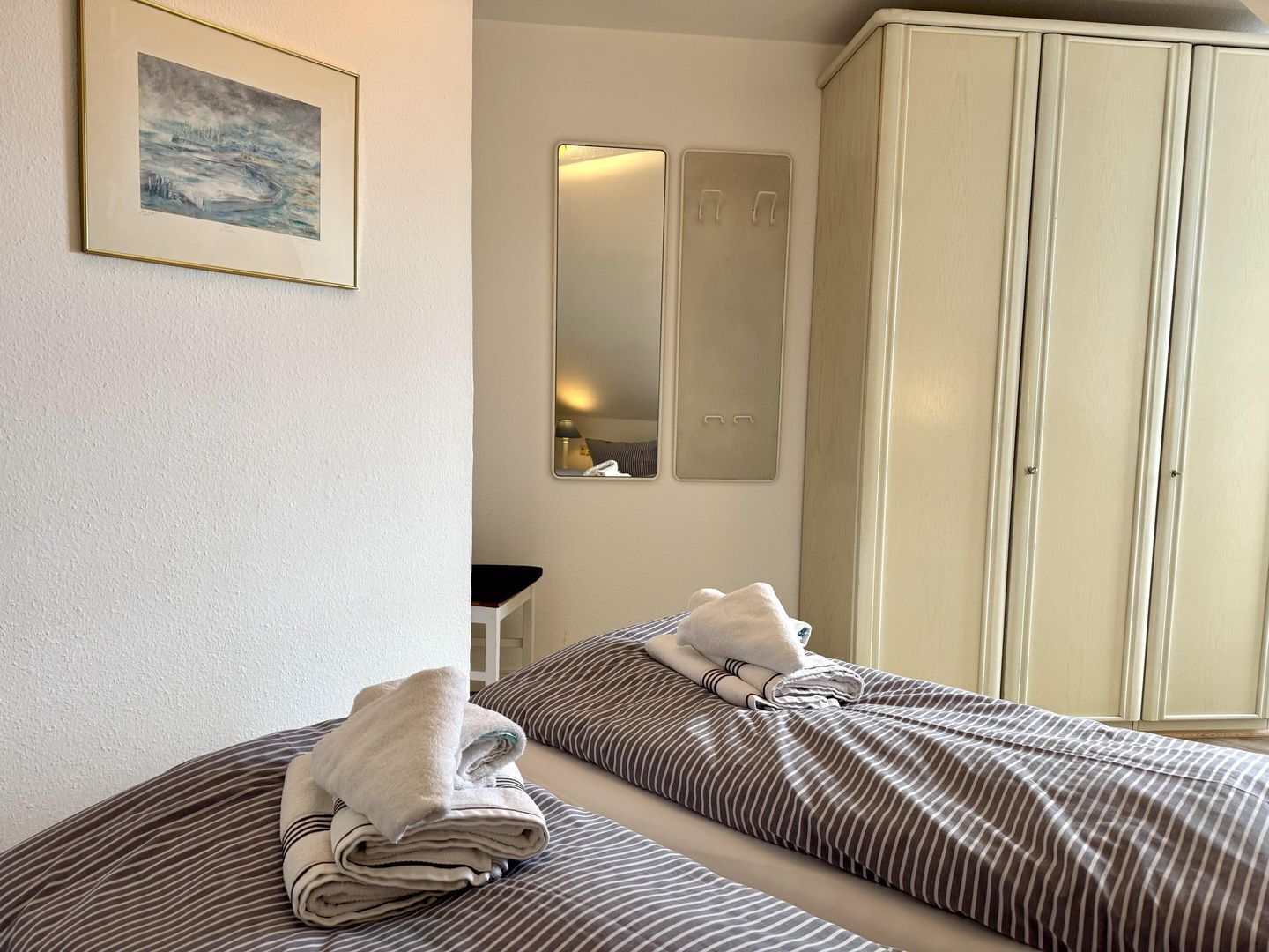 Ein Hotelzimmer mit Bett, Kleiderschrank, Spiegel und einem gerahmten Bild an der Wand.