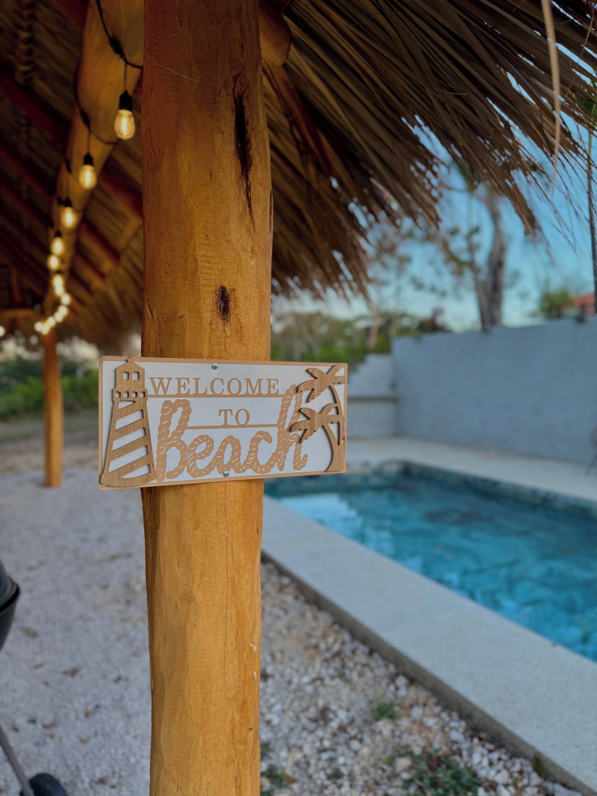 Un letrero de madera que dice 'WELCOME TO Beach', sujeto a un poste de madera.