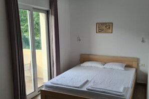 A bedroom with a bed, a window with curtains, a wall-mounted light, and a framed picture. - Villa Ponto - Studio Apartment With Terrace (A5) (Kaluderac)