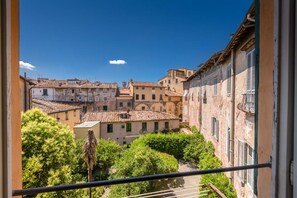 Blick auf eine historische Stadt mit traditioneller Bebauung, einem Balkon und üppiger Bepflanzung.