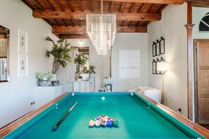 A pool table with balls and a cue stick, surrounded by framed artwork and potted plants. - Refined 3-Bedrooms Apartment In Palazzo Busdraghi (Lucca)