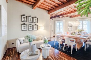Un salon moderne avec un canapé, une table basse et un coin repas comprenant des chaises et une table mise pour le repas.