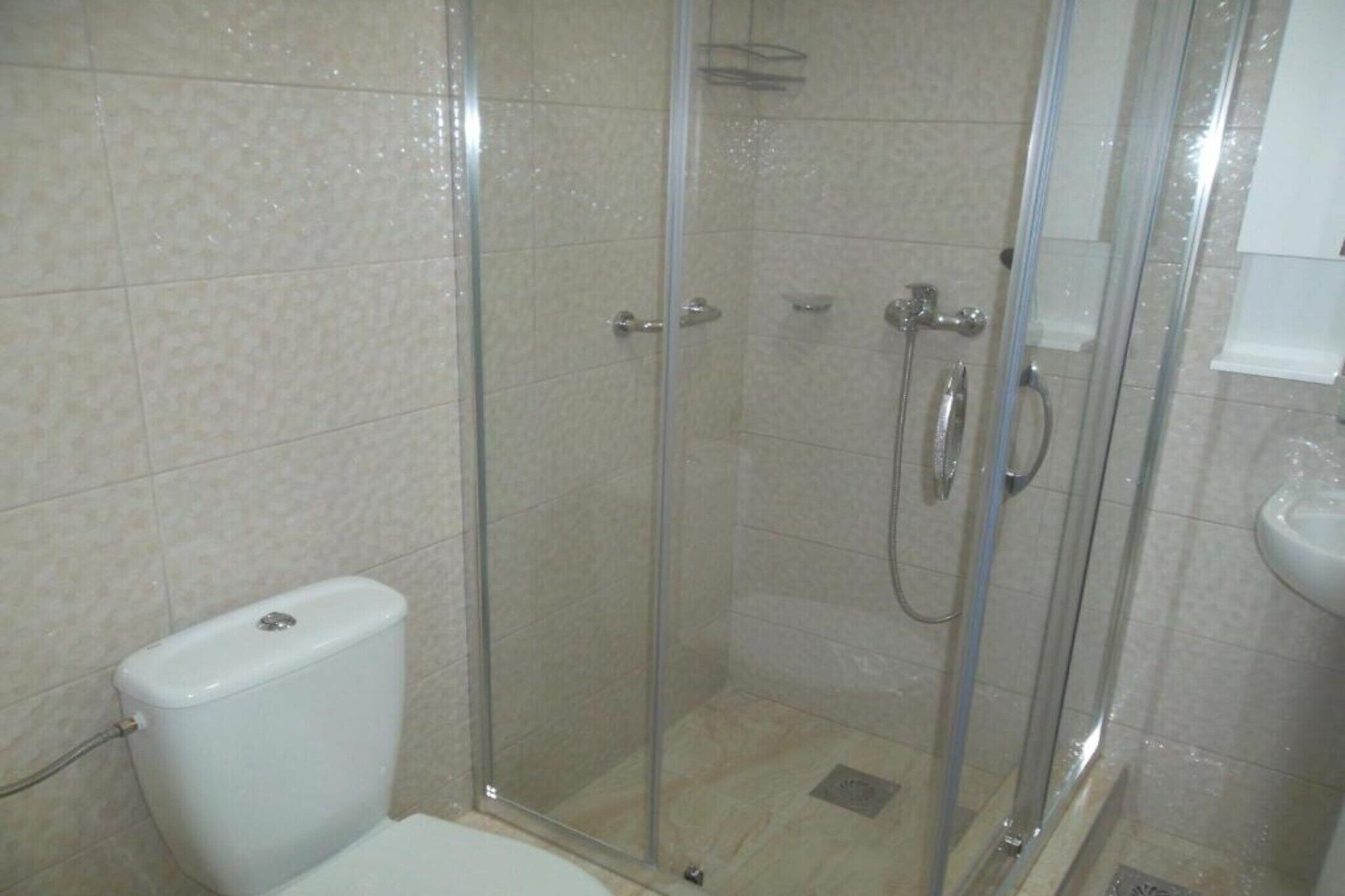 A shower enclosure with a glass door, a toilet, and a sink.