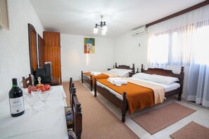 A hotel room with two beds, a dining table with a bottle of wine and glasses, a television, and a painting on the wall. - Guest House 4M Gregović - Double bed Lux 12 (Petrovac na Moru)