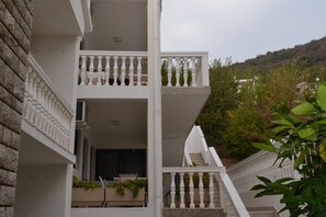 A multi-story building with balconies, a staircase, and a view of a hillside. - Guest House 4M Gregović - Double bed Lux 12 (Petrovac na Moru)