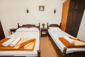 A hotel room with two beds, a nightstand, a small table with a vase, and a wooden wardrobe. - Guest House 4M Gregović - Triple bed Studio 4 (Petrovac na Moru)