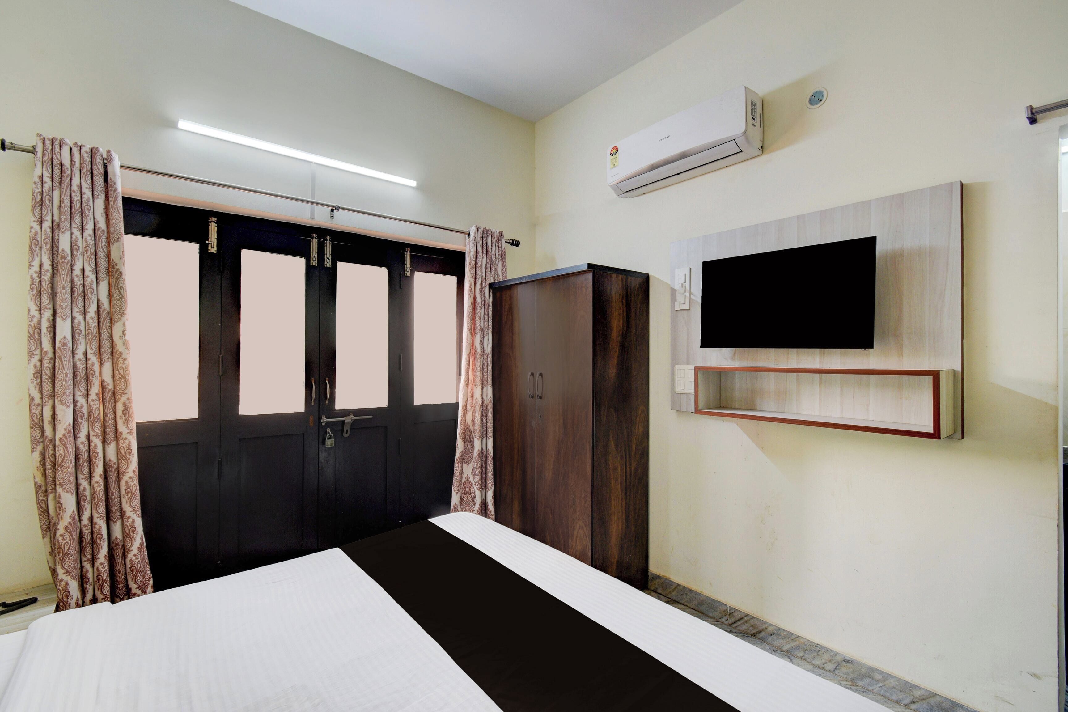 A bedroom with a bed, wardrobe, and a mounted TV.