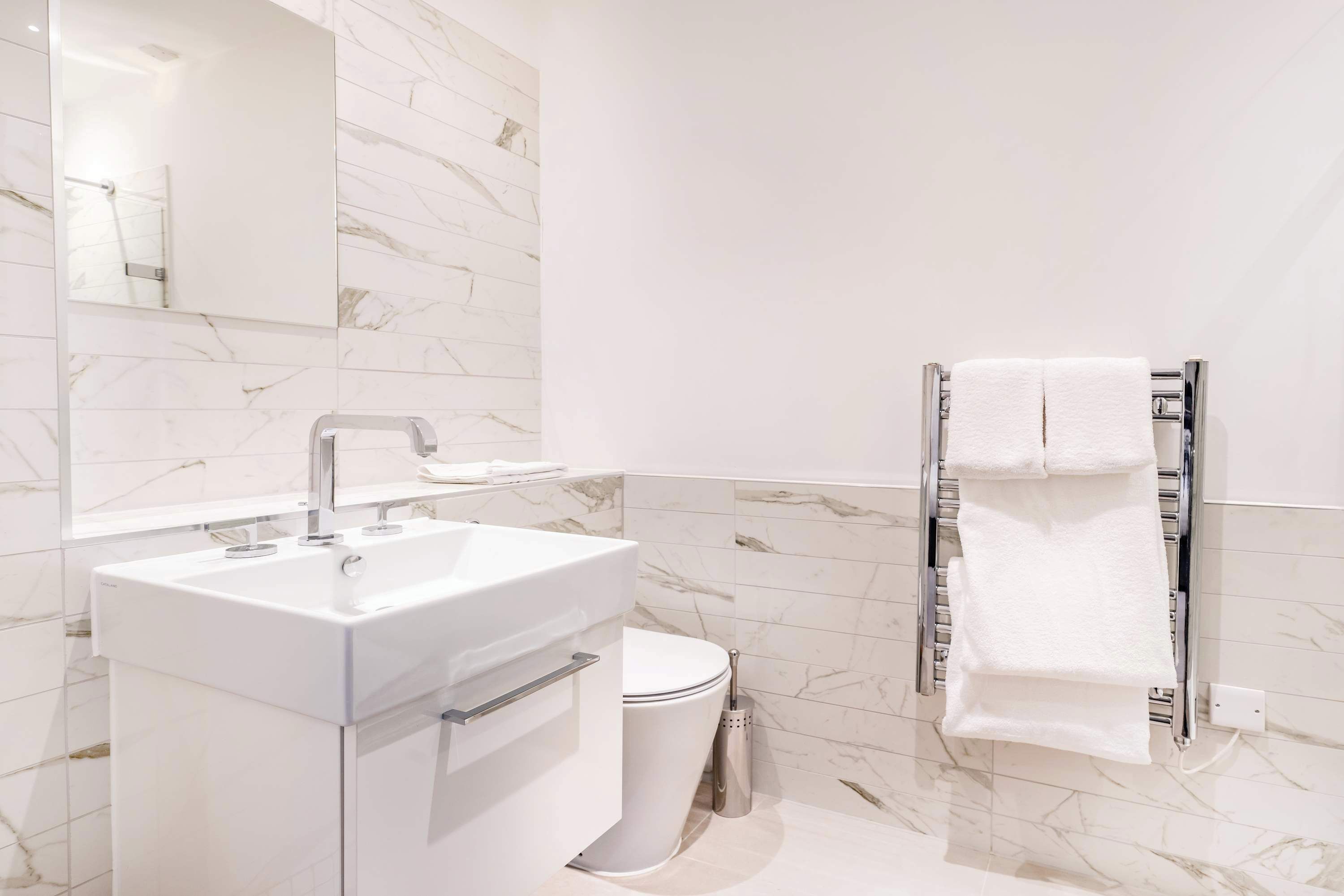 A modern bathroom with a white sink, toilet, and a towel rack.