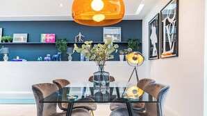 A modern dining area with a glass table, velvet chairs, and a central vase. - The Colour Brief at No. 64 (London)