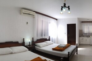 Quarto de hotel com duas camas, uma cozinha compacta e um banheiro.