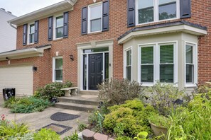 A two-story brick house with a black front door, white shutters, and a bay window. - Easy Transit to DC! Family Home w/ Fenced Yard (Springdale)