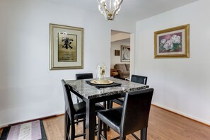 A dining area with a marble table, black chairs, and framed artwork on the walls. - Easy Transit to DC! Family Home w/ Fenced Yard (Springdale)