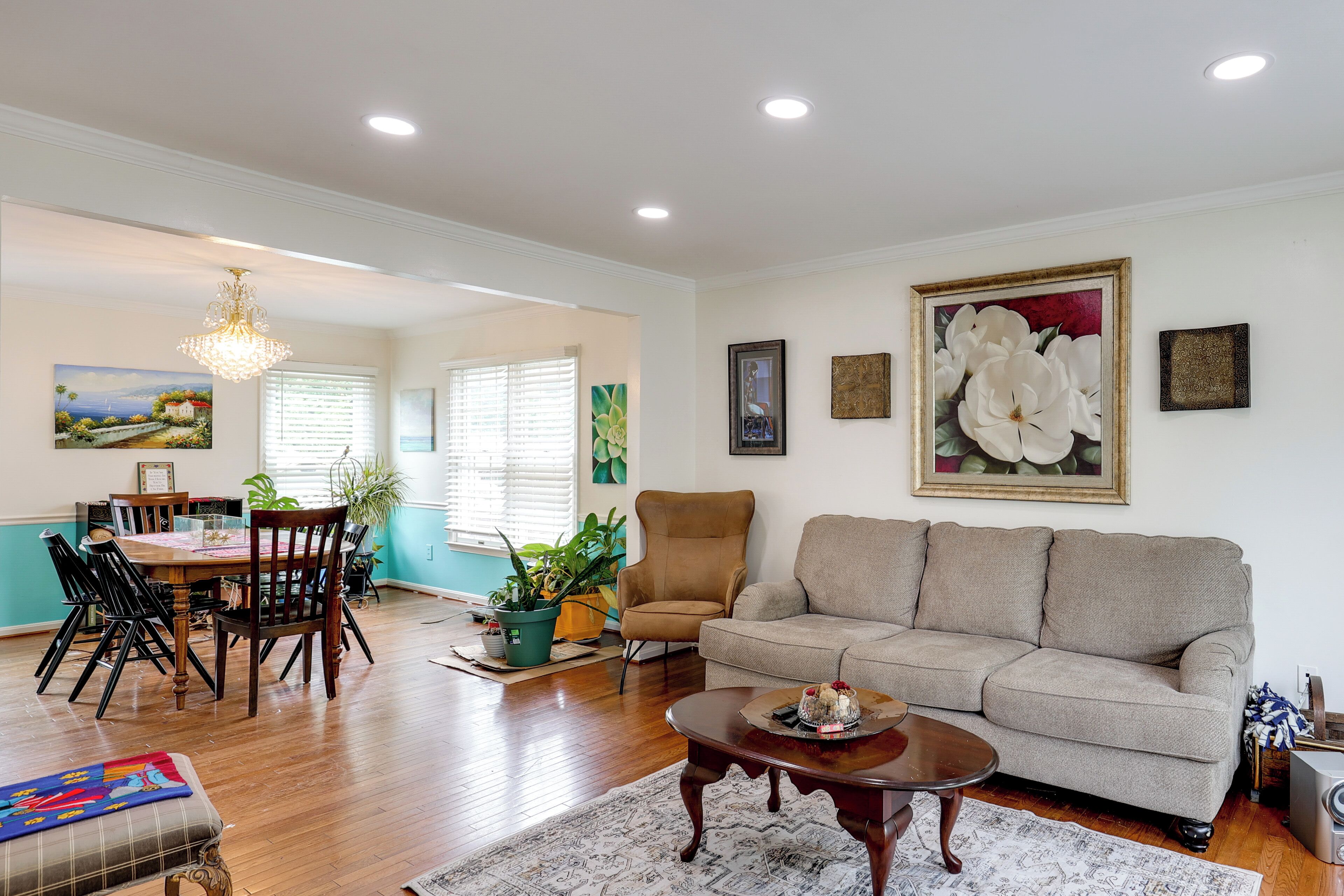 A spacious living room with a sofa, a dining area with a table and chairs, and a chandelier.