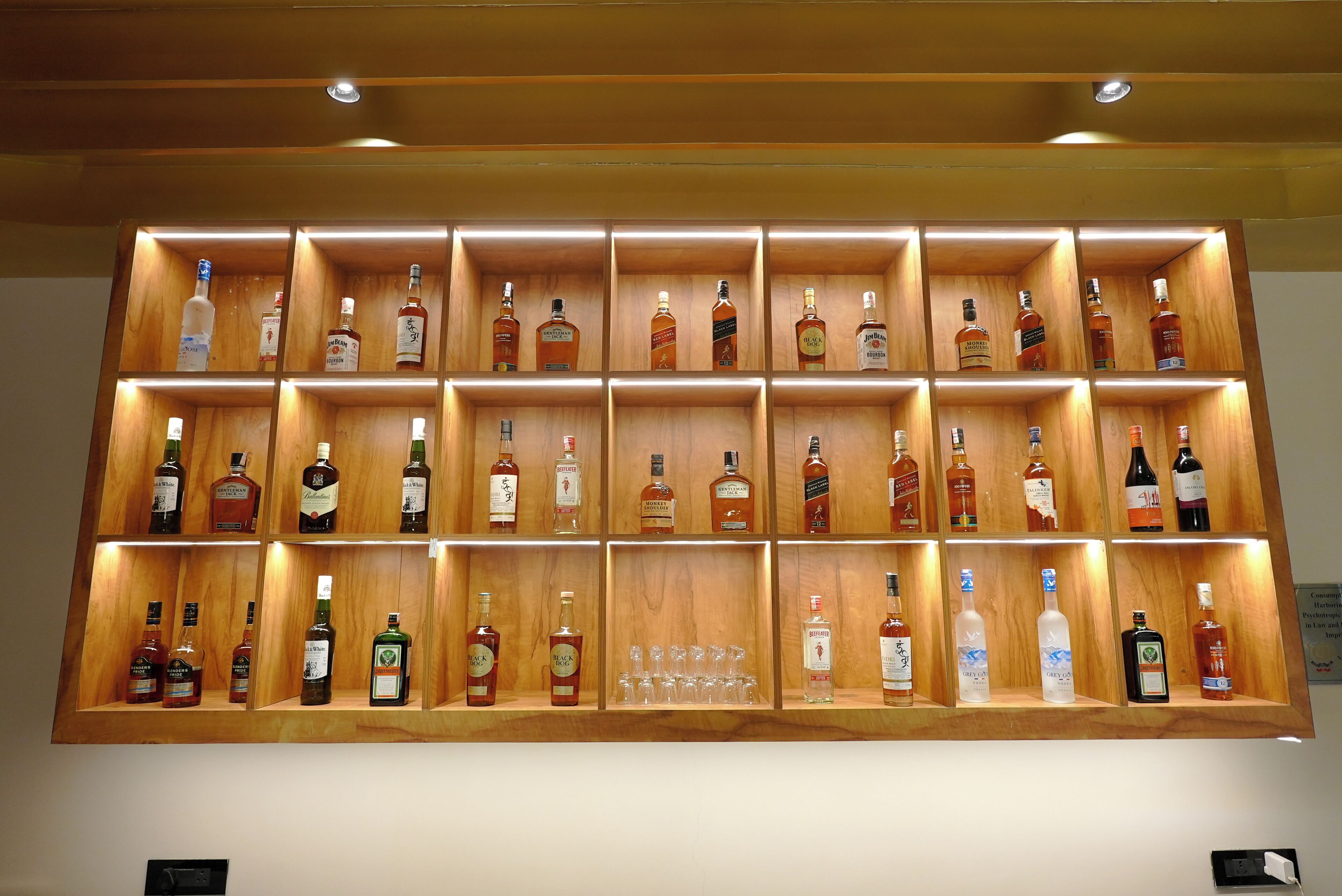 A wall of neatly organized liquor bottles in wooden shelves.