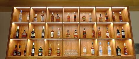 A wall of neatly organized liquor bottles in wooden shelves.