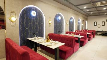 A restaurant with red upholstered booths, tables set with plates and cutlery, and decorative wall sconces.