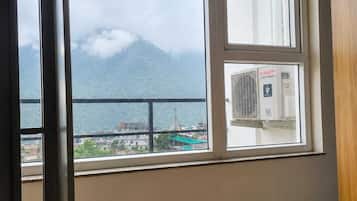 Una habitación con un ventanal grande que da a una masa de agua y una montaña, con un equipo de aire acondicionado visible en el alféizar.