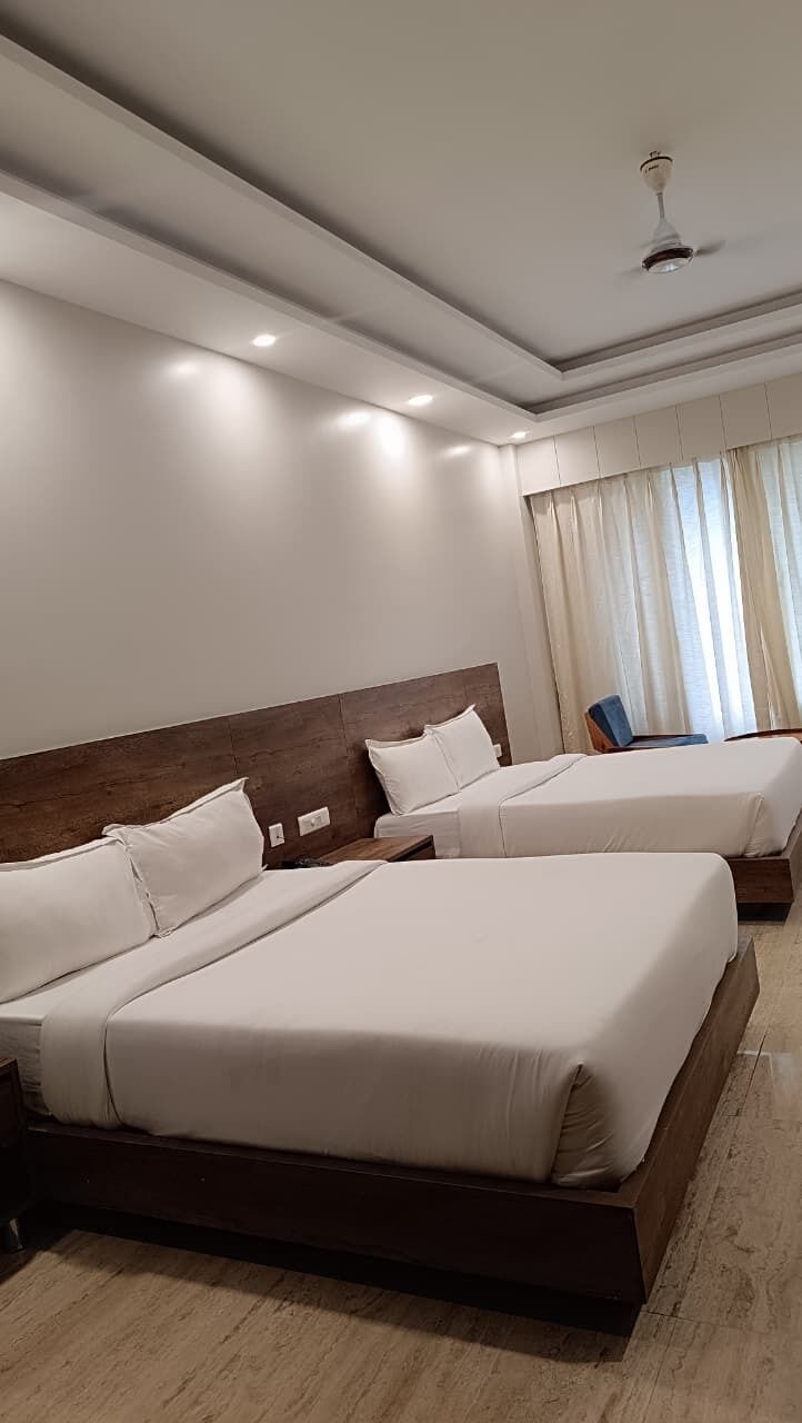 A hotel room with two beds, a wooden headboard, a ceiling fan, and a window with curtains.