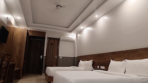 A hotel room with two beds, a wooden headboard, a flat-screen TV, and an air conditioning unit. - Royalistiq (Rishikesh)