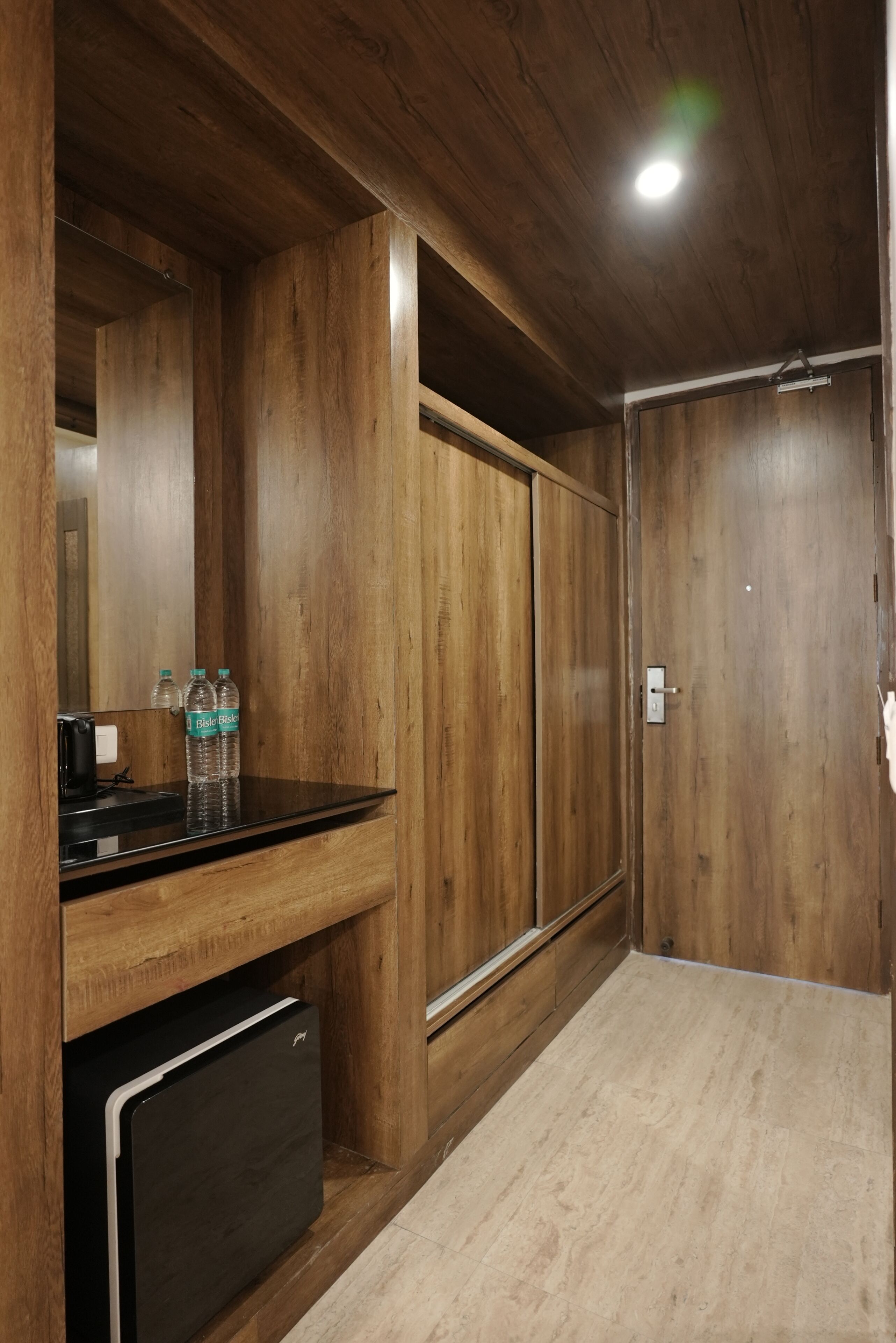 Una habitación con paneles de madera, una kitchenette, un espejo y una puerta.