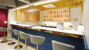 A bar area with a counter, stools, and shelves of bottles. - Royalistiq (Rishikesh)