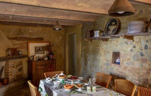 A rustic dining area with a stone wall, wooden furniture, and a variety of dishes and drinks on the table. - Lovely home in Cinigiano (Cinigiano)