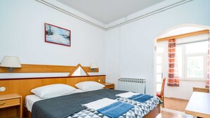 A hotel room with a bed, bedside tables, a window with curtains, a radiator, and a painting on the wall. - Apartments Klis -studio Apartment With Terrace - 2 (Zupa dubrovacka)