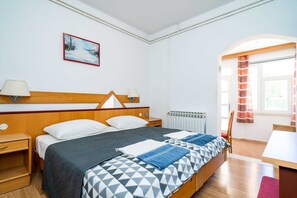 A hotel room with a bed, bedside tables, a window with curtains, a radiator, and a painting on the wall. - Apartments Klis -studio Apartment With Terrace - 2 (Zupa dubrovacka)