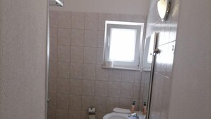 Ein kleines Badezimmer mit Toilette, Waschbecken und Dusche.