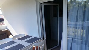 Ein Balkon mit Tisch und Stühlen, eine Schiebeglastür und Blick ins Freie.