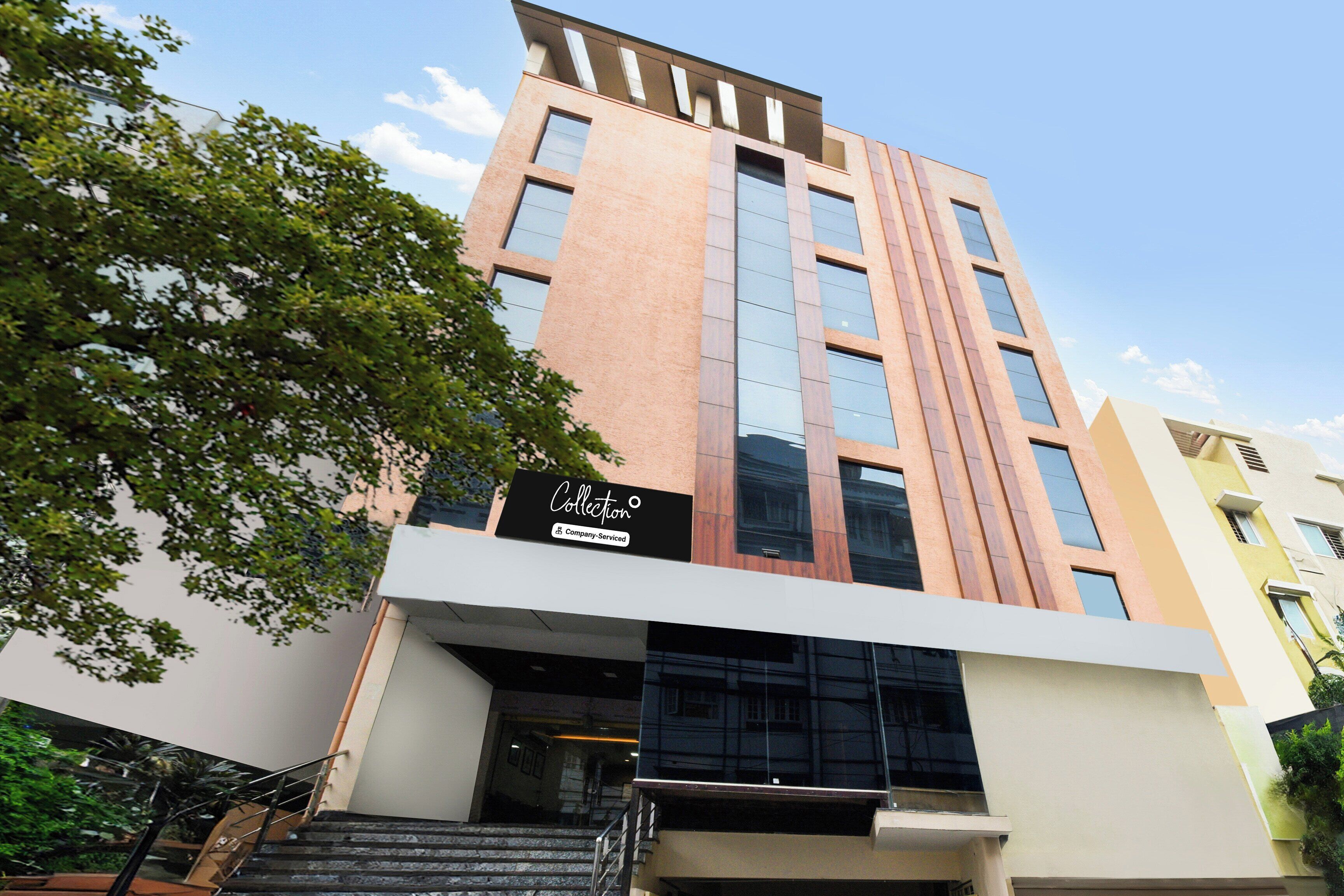 A multi-story building with a modern architectural design, featuring a prominent entrance with a staircase leading to the ground level.