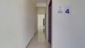 A corridor with a tiled floor, a door with a number 4 sign, and a no smoking, no alcohol sign on the wall. - Super Collection O Manikonda (Hyderabad)