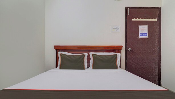 A single bed with a wooden headboard, two pillows, and a red and black bedspread. - Super Collection O Manikonda (Hyderabad)